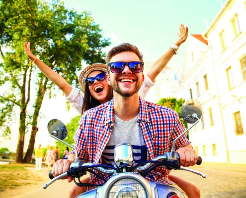 Man driving a moped with women on back